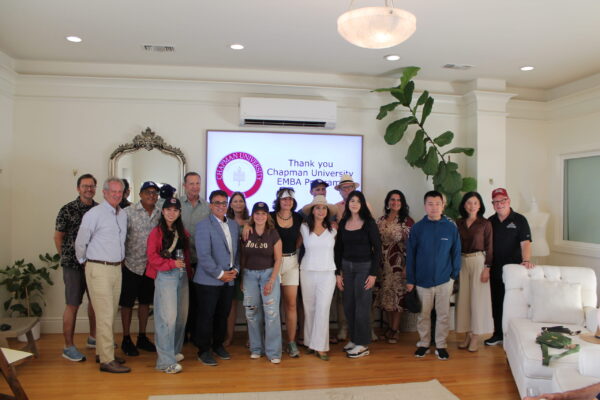 Chapman Executive MBA students and faculty pose for a group photo in front of a screen displaying the Chapman University logo and a thank-you message.