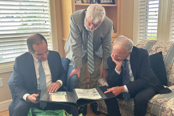Matt Parlow, Daniele Struppa, and Jim Doti look through a scrapbook of Chapman memorabilia together.