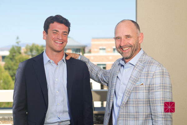 Matt Salerno and Alex Hayden smile on a balcony with a view of Chapman in the background.