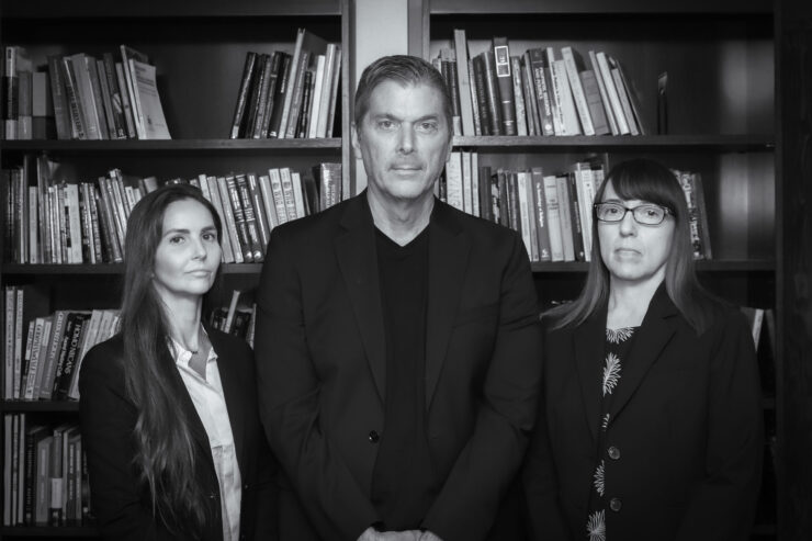 Ashley Kranjac, Christopher Bader, and Ann Gordon stand in front of bookshelves in a black-and-white portrait.