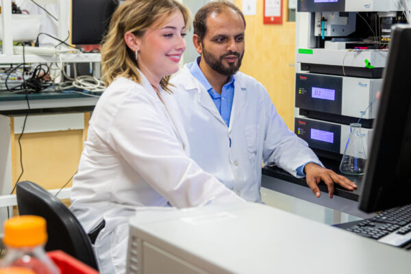 A pharmacy student works in the lab alongside an instructor.