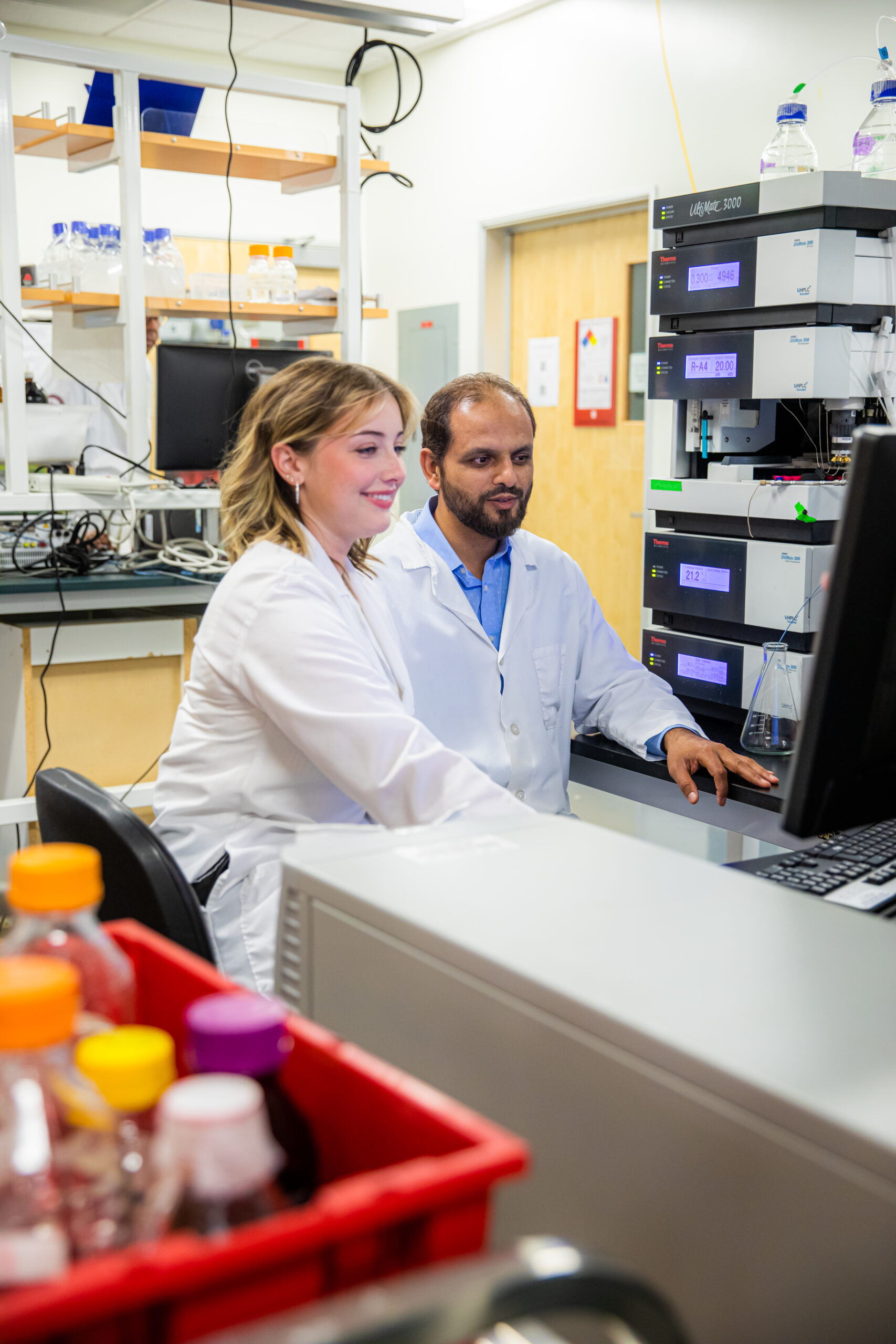 A pharmacy student works in the lab alongside an instructor.